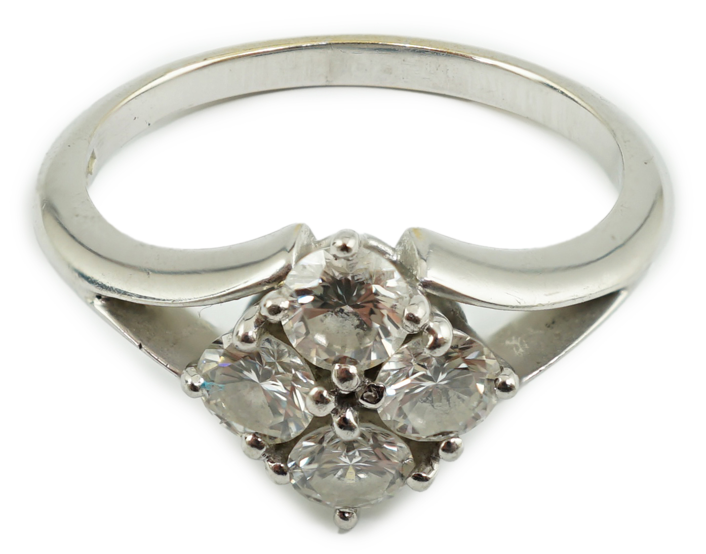 A modern platinum and four stone diamond cluster set ring